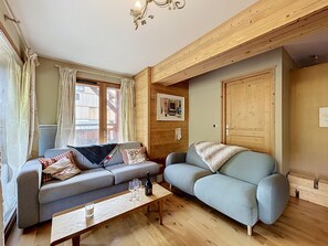 A cozy living room with two sofas, a wooden coffee table, and a chandelier. - Acoya - Les Gets - ski-in/ski-out (Les Gets)