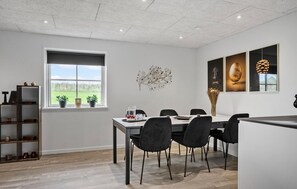 Ein stilvoller Essbereich mit Tisch und Stühlen, einem Fenster mit Pflanzen und Kunstwerken an der Wand.