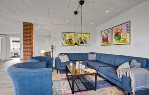 Ein modernes Wohnzimmer mit einem blauen Sofa, einem Couchtisch und farbenfroher Kunst an den Wänden.