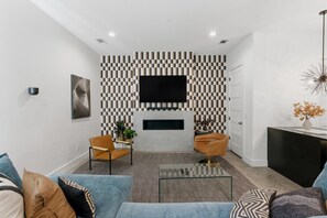 A modern living room with a checkered wall pattern, a flat-screen TV, a fireplace, and two armchairs. - Downtown Rooftop Sleeps 10 Near Gulch and 12 South (Nashville)