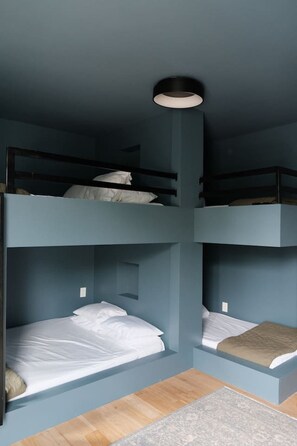 Ein Schlafzimmer mit Etagenbett, wobei unten ein Einzelbett und darüber ein Kopfteil mit einer Lampe angebracht sind.