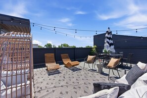 Eine Terrasse im Freien mit Holzliegen, einem Tisch und Lichterketten.