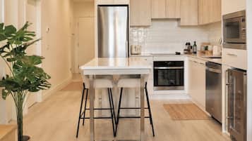 Una cocina moderna con una isla central, electrodomésticos de acero inoxidable y armarios de madera clara.