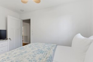 A bedroom with a bed, a television on a dresser, and a door leading to another room. - Sleeps 12 - Dog-Friendly Nashville Cottage (Nashville)