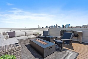 A rooftop terrace with a sofa, chairs, a fire pit, and a view of the city skyline. - Luxury Nashville Urban Cowboy Rooftop | Sleeps 10 (Nashville)