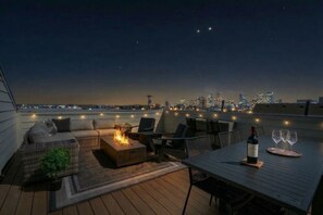 A rooftop terrace with a fire feature, seating, and a table with wine glasses. - Luxury Nashville Urban Cowboy Rooftop | Sleeps 10 (Nashville)