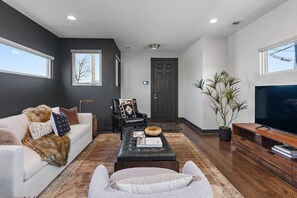 A modern living room with a sofa, a coffee table, a television, and a large potted plant. - Luxury Nashville Urban Cowboy Rooftop | Sleeps 10 (Nashville)