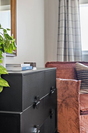 A modern living room with a black cabinet, a plant, and a red sofa. - Luxury Nashville Urban Cowboy Rooftop | Sleeps 10 (Nashville)