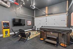 A room with a large flat-screen TV, a Pac-Man arcade machine, exercise equipment, and a bunk bed with a storage chest. - 8BR Nashville Duo - Rooftops Hot Tubs - sleeps 24 (Nashville)