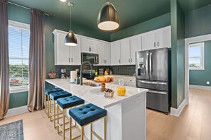 A modern kitchen with a central island, bar stools, stainless steel appliances, and a view of the outdoors. - 8BR Nashville Duo - Rooftops Hot Tubs - sleeps 24 (Nashville)