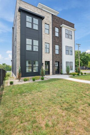 A modern multi-story residential building with a flat roof, large windows, and a well-maintained lawn. - 8BR Nashville Duo - Rooftops Hot Tubs - sleeps 24 (Nashville)