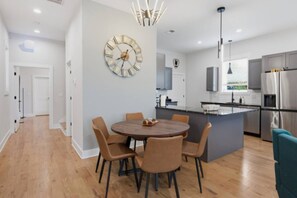 A modern kitchen with stainless steel appliances, a round dining table with chairs, and a wall clock. - Modern Nashville Retreat Near Downtown & Music Row (Nashville)