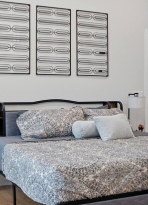 A bedroom with a bed, patterned bedding, a headboard, and three wall-mounted artworks. - Modern Nashville Retreat Near Downtown & Music Row (Nashville)