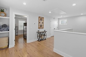 A spacious room with a wooden floor, white walls, and a central table with a decorative item. - Modern Nashville Retreat Near Downtown & Music Row (Nashville)