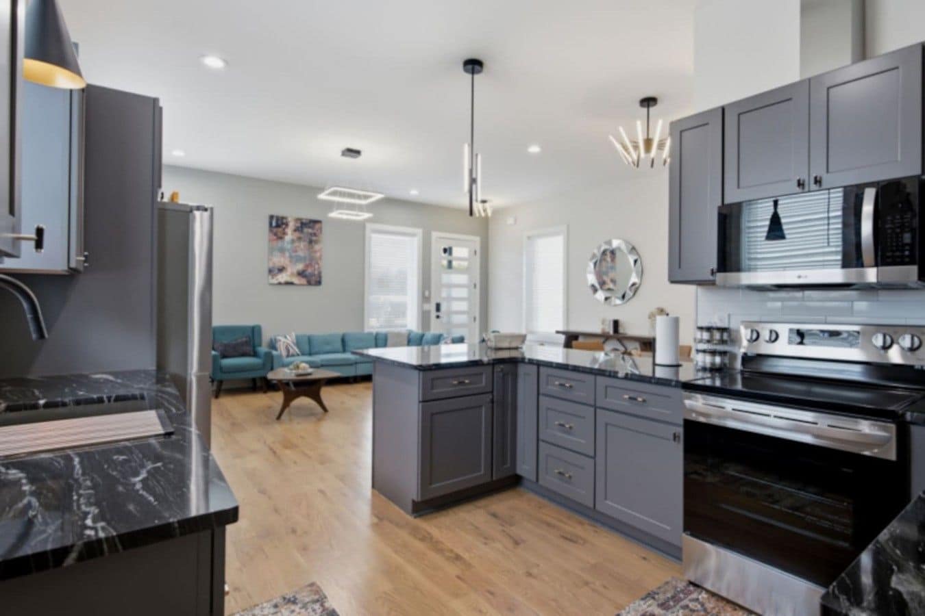 A modern kitchen with grey cabinets, a central island, and stainless steel appliances.