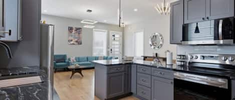 A modern kitchen with grey cabinets, a central island, and stainless steel appliances.