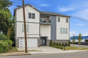 Ein zweistöckiges Wohnhaus mit Garage, Balkon und gepflegtem Rasen.