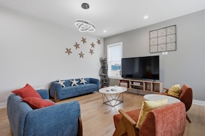 Een woonkamer met een bank, stoelen, een salontafel, een televisie en decoraties met zeesterren.