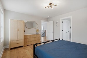 Ein Schlafzimmer mit Bett, Kleiderschrank, Spiegel und einer Tür zu einem anderen Raum.