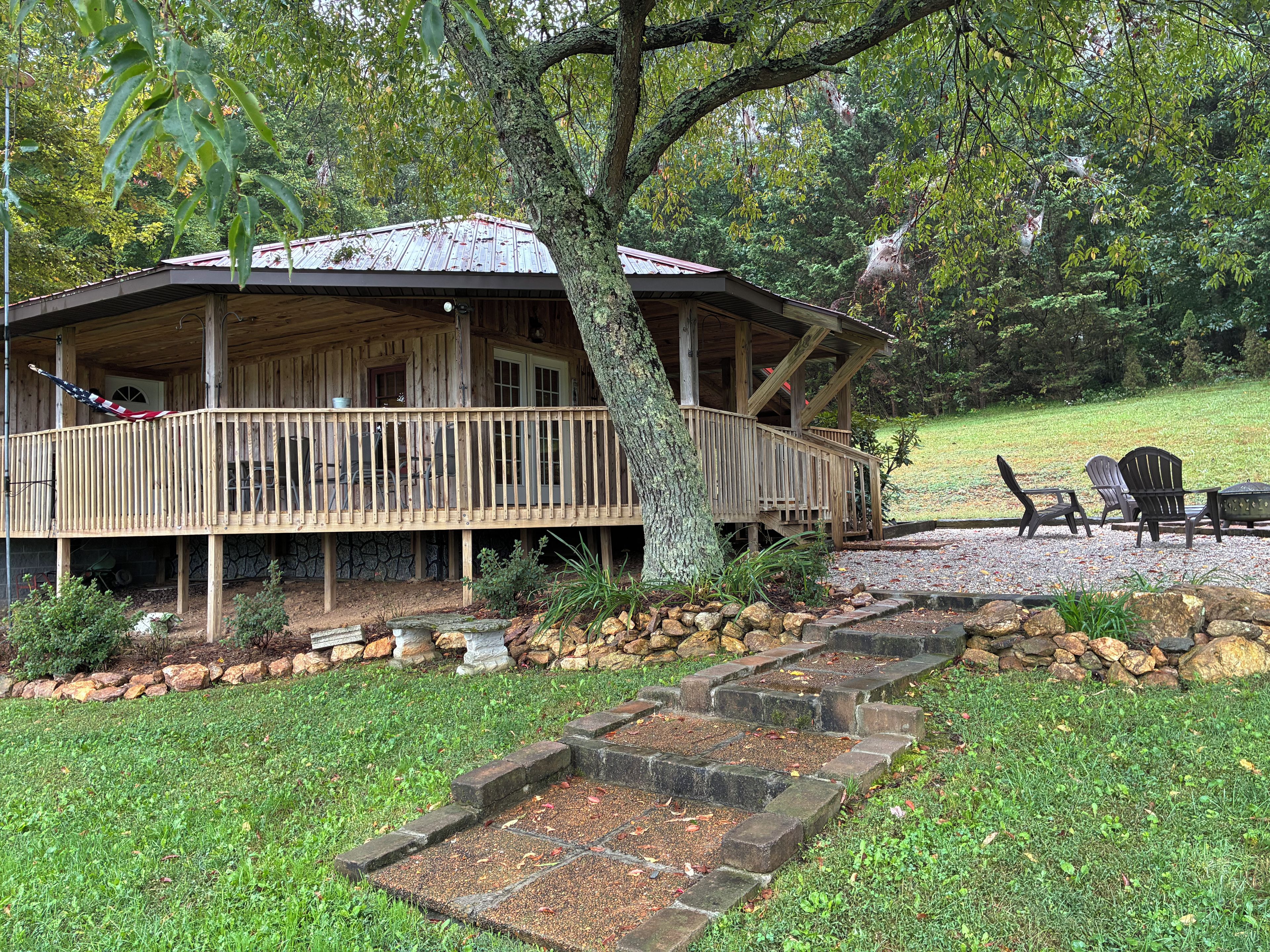 A wooden cabin with a porch, a stone pathway, and outdoor seating.