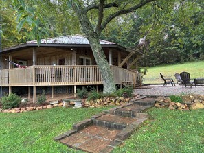 Una baita di legno con veranda, un vialetto in pietra e posti a sedere all'aperto.