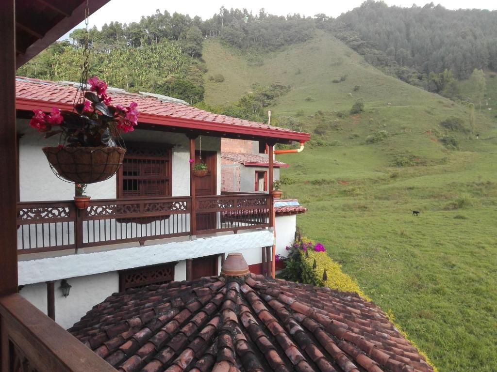 A building with a red-tiled roof, a balcony with a wooden railing, and a hanging flower pot.