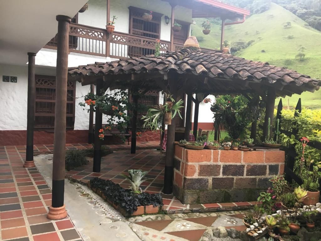 A covered outdoor area with a tiled floor, a brick planter with various plants, and a wooden pergola structure.