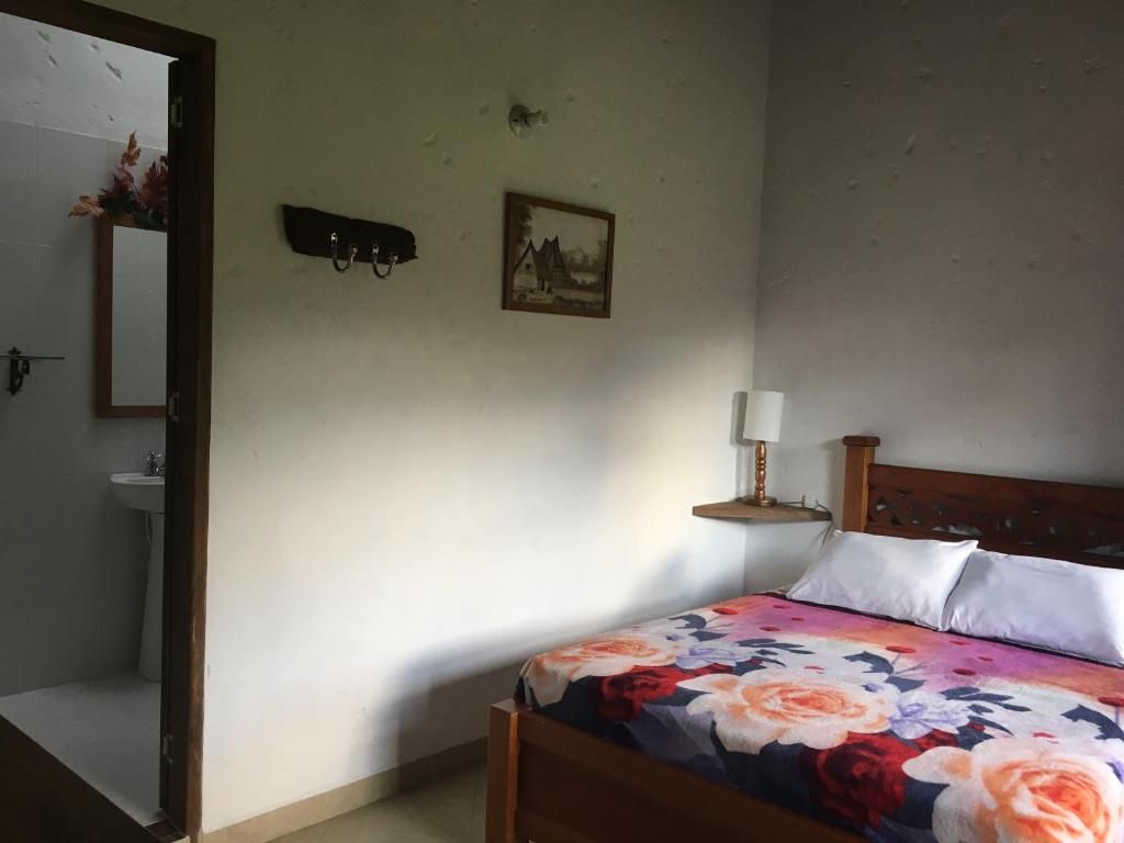 Une chambre à coucher comprenant un lit, une table de chevet avec une lampe, une étagère fixée au mur et un miroir.