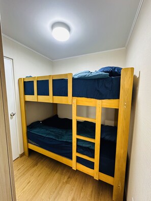 A bunk bed with a wooden frame and blue bedding, a white door, and a wooden floor. - Dept. Brand-New, Central, and Modern Family Home (Pet-Friendly and Free Parking) (Lima)