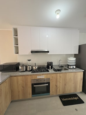 A compact kitchen with white cabinets, a built-in oven, a stove, and various appliances on the countertop. - Dept. Brand-New, Central, and Modern Family Home (Pet-Friendly and Free Parking) (Lima)