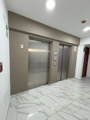 A hallway with two elevators and a fire alarm on the wall. - Dept. Brand-New, Central, and Modern Family Home (Pet-Friendly and Free Parking) (Lima)