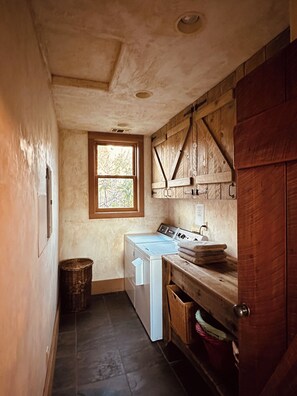 A laundry room with a washing machine, a wooden cabinet, a window, and a door. - Spacious and secluded ranch getaway on 200 acres (Grass Valley)