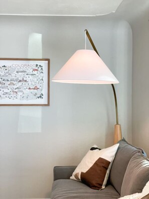 Ein Zimmer mit einer grauen Couch, einer gerahmten Karte von Colorado und einer Lampe mit weißem Lampenschirm.