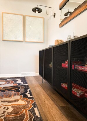 A room with a patterned rug, a black metal cabinet with red boxes, and two wall-mounted light fixtures.