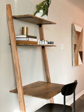 Eine an der Wand befestigte Holzregal mit Büchern, Dekoration und einem Blumentopf.