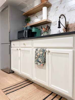 A kitchen with white cabinets, a stainless steel refrigerator, a wooden countertop, and a backsplash.