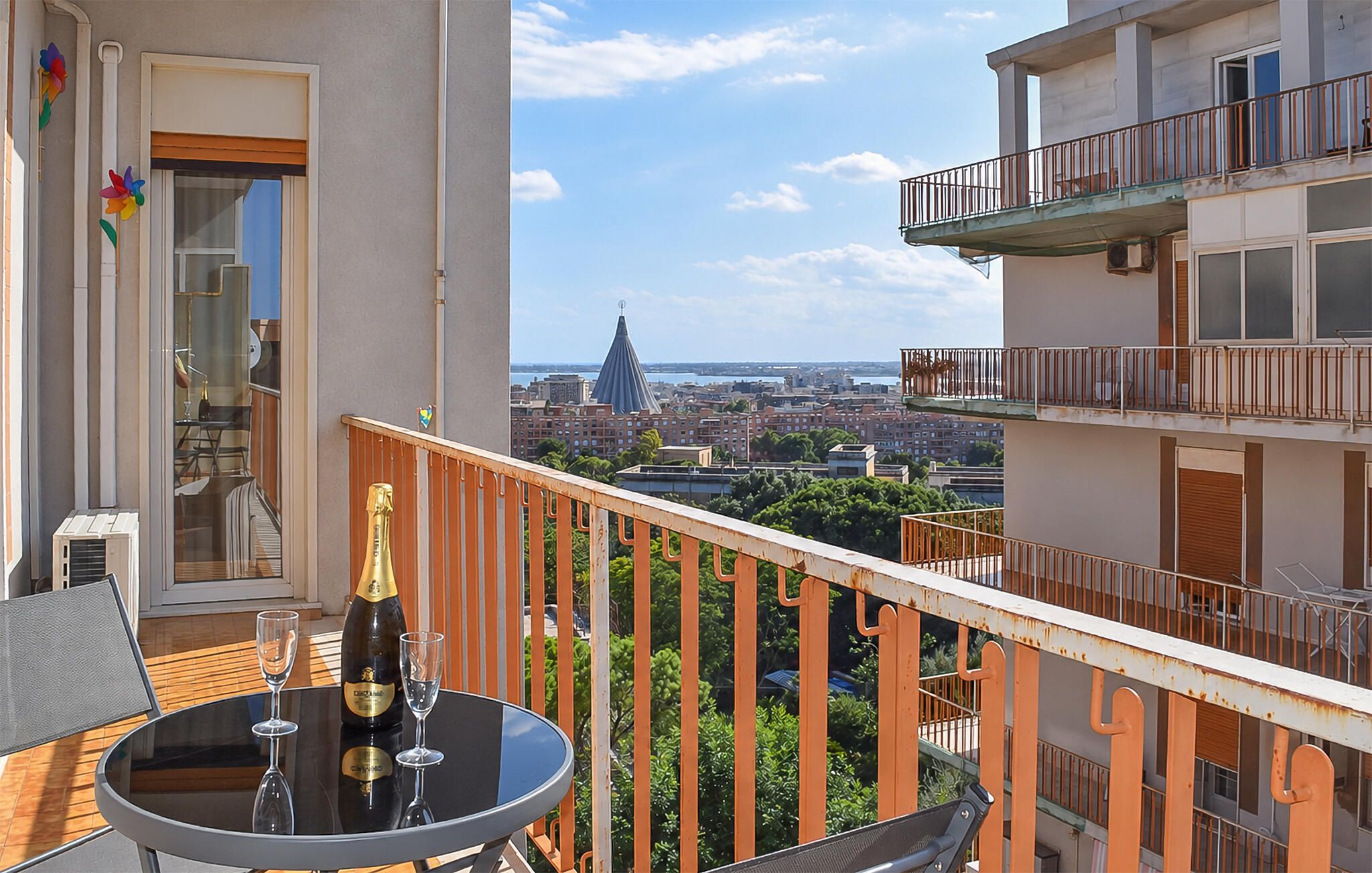 A balcony with a table and chairs, a bottle of champagne, and a glass.