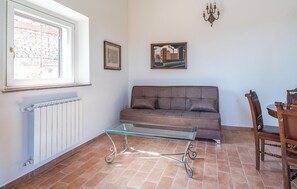A living room with a sofa, a glass coffee table, a radiator, a window, a map, a painting, and a chandelier. - Podere la Terrazza con Idromas (Prata)