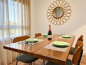 A dining area with a wooden table, green plates, and a bottle of wine. - ALBACETELOFT Modern 2-bedroom apartment | Wi-Fi | Ideal for Work and Family (Albacete)