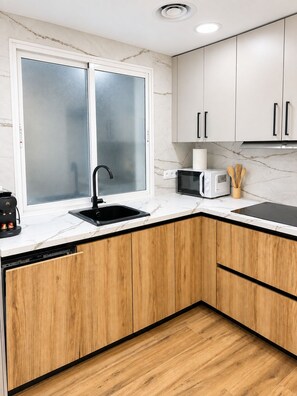 A kitchen with a double sink, a microwave, and wooden cabinets. - ALBACETELOFT Modern 2-bedroom apartment | Wi-Fi | Ideal for Work and Family (Albacete)