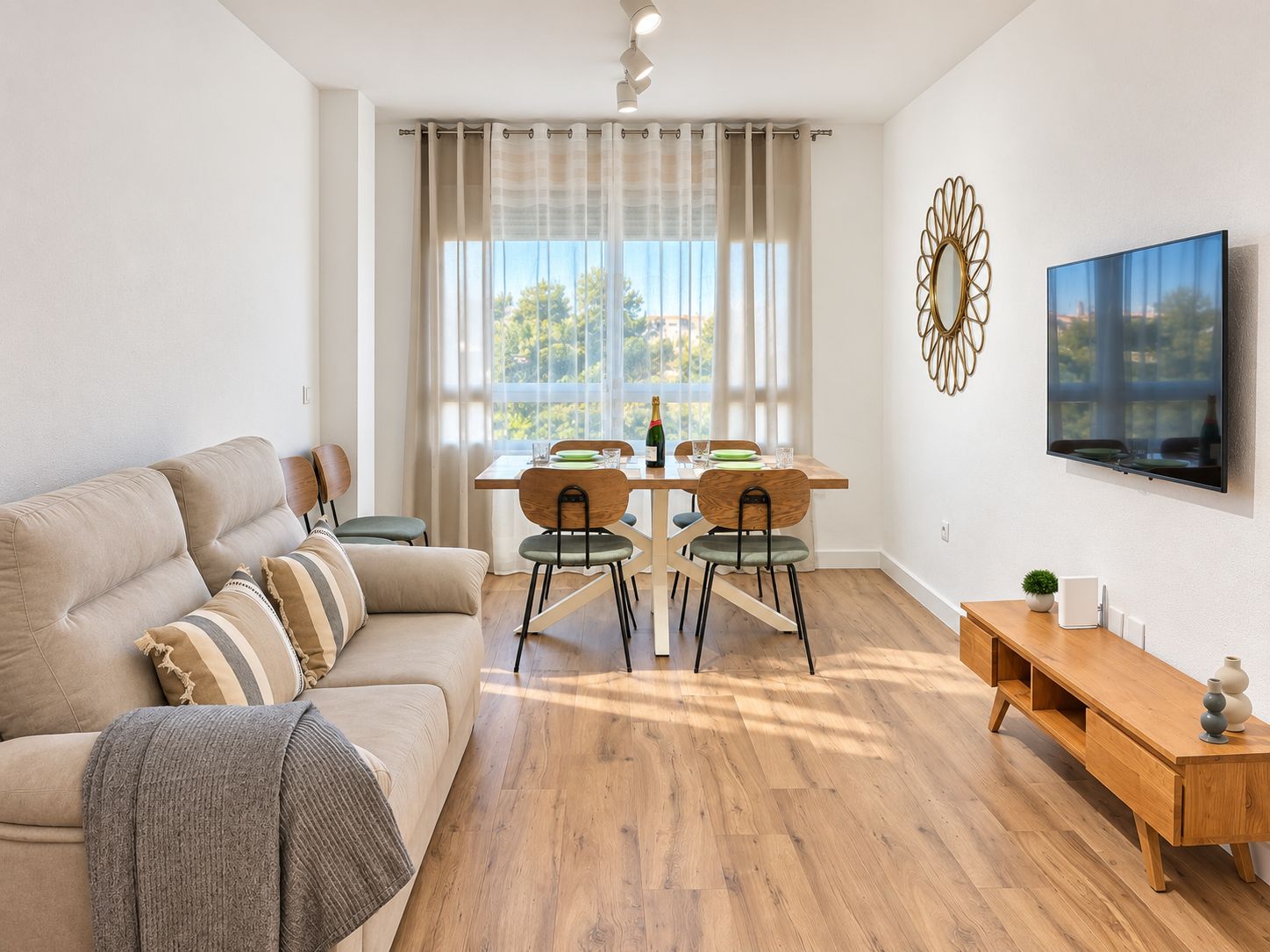 Un salon moderne comprenant un canapé, une table à manger, des chaises et un téléviseur.