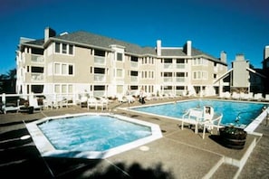 Et hotel med flere balkoner, swimmingpool og liggestole.