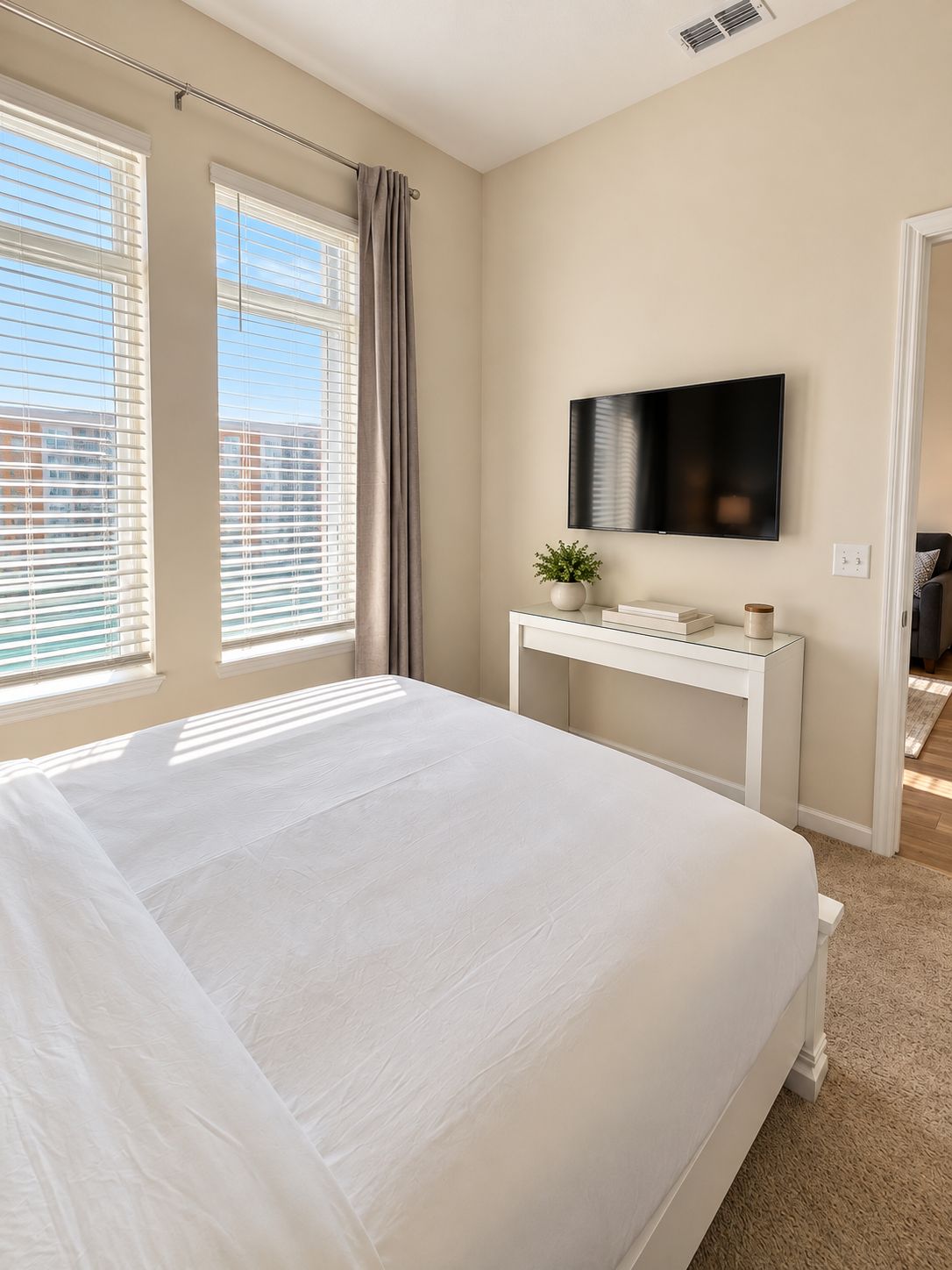 Bright, serene bedroom with wall-mounted TV and abundant natural light