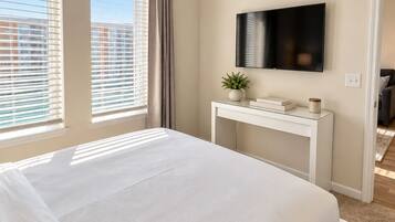 Bright, serene bedroom with wall-mounted TV and abundant natural light