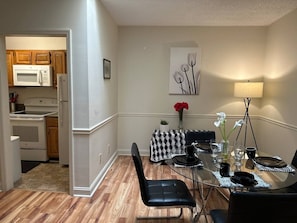 A dining area with a glass table, black and white checkered tablecloth, black chairs, and a vase with red flowers. - Downtown 2 Bedrooms: Walk to Everything (Greensboro)