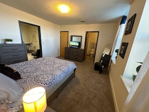 A bedroom with a bed, dresser, and a television. - Downtown Lounge Getaway with Two Living Spaces (Greensboro)