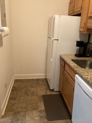 A compact kitchen with a refrigerator, a coffee maker, and a dishwasher. - Chic Cozy One Bedroom Walkable Downtown (Greensboro)