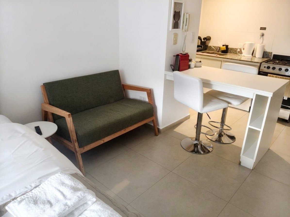 Un espace de vie compact comprenant un canapé, une petite table à manger et un coin cuisine.