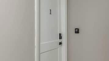 A hallway with a white door marked with the number 1, a light switch, and a wooden trim at the base.