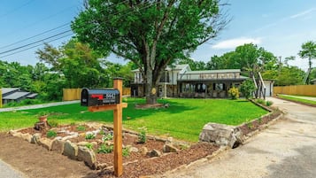 A residential property with a mailbox, a well-maintained lawn, and a large tree.